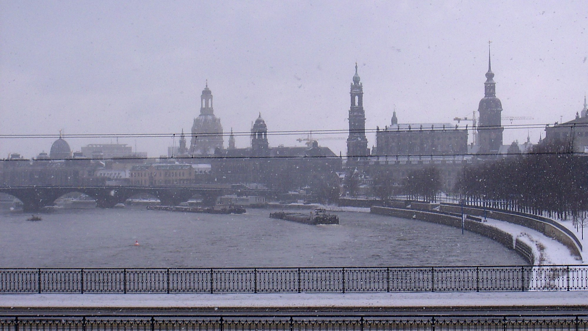 Aus dem Zugfenster ist in dichtem Schneetreiben das Elbpanorama von Dresden zu erkennen.