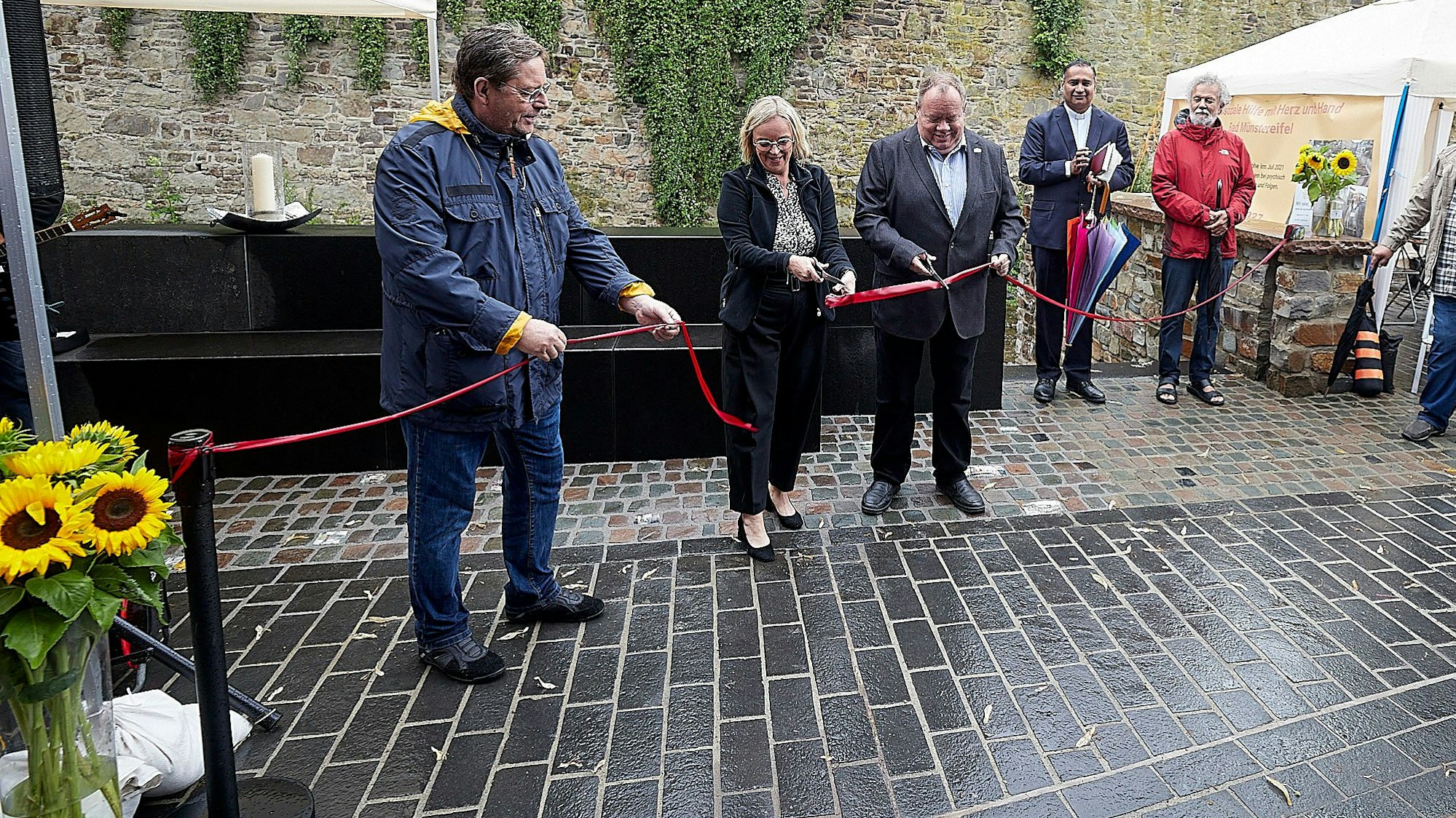 Mehrere Männer und eine Frau durchtrennen ein rotes Band.