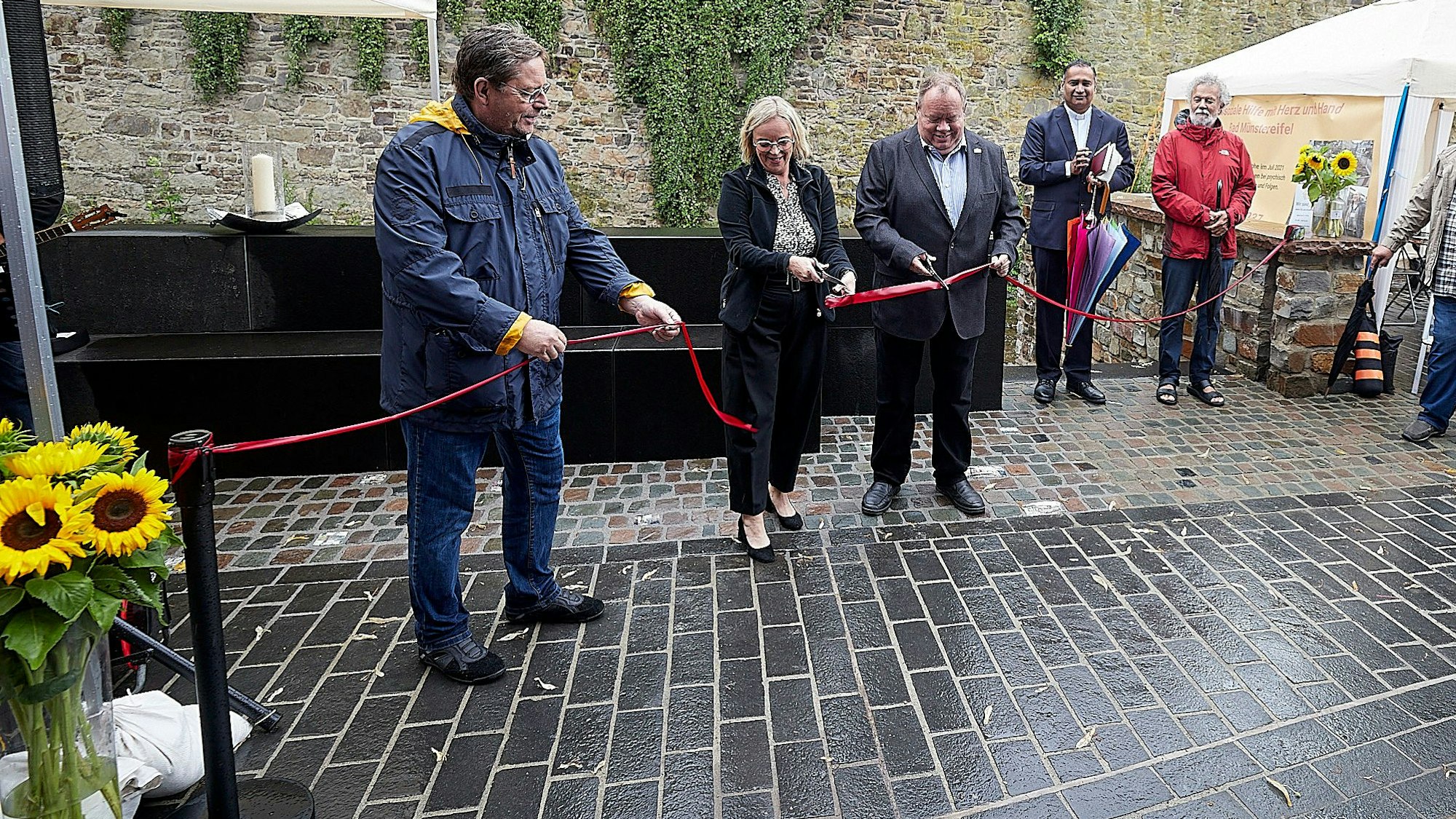Mehrere Männer und eine Frau durchtrennen ein rotes Band.