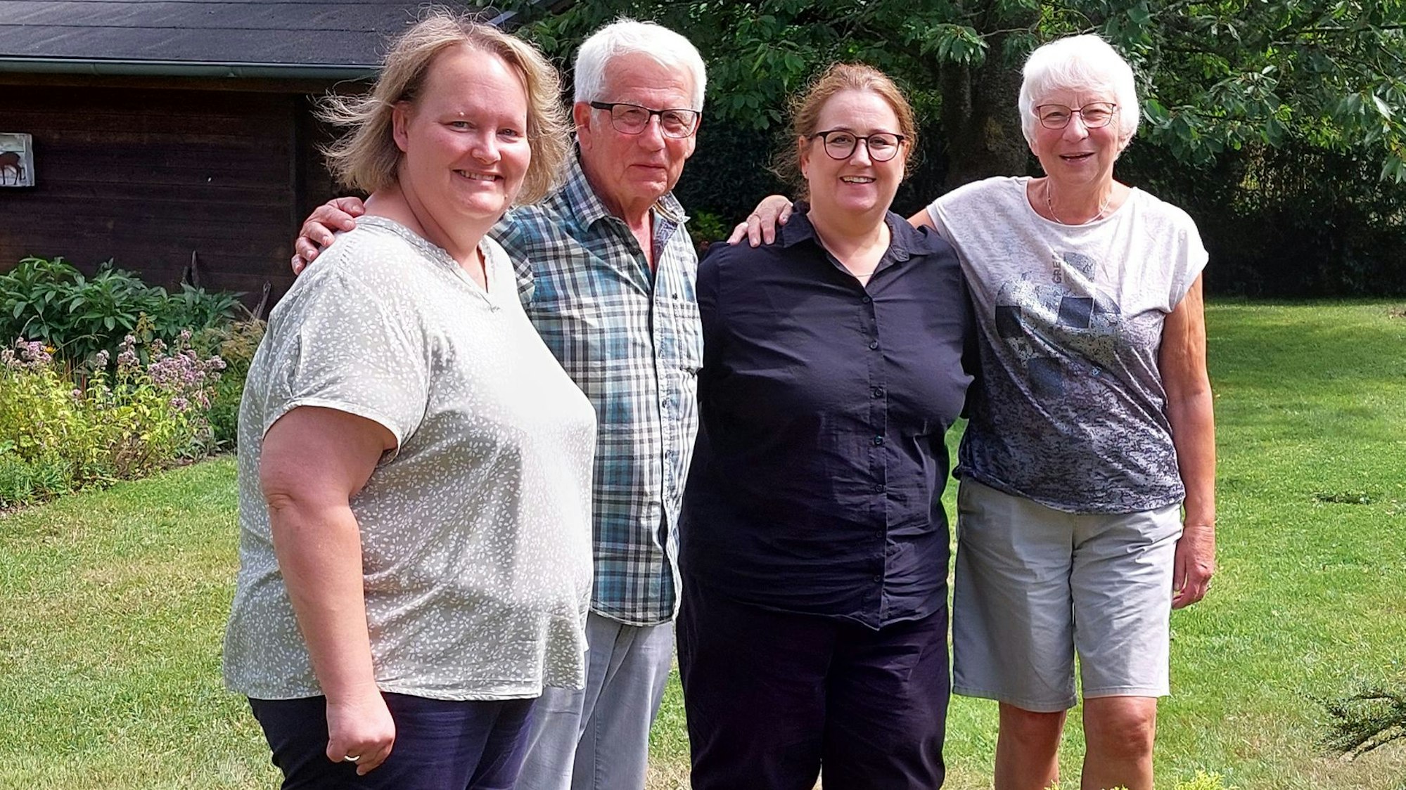 Vier Personen stehen in einem Garten und betrachten den Wiederaufbau nach der Flutkatastrophe 2021.