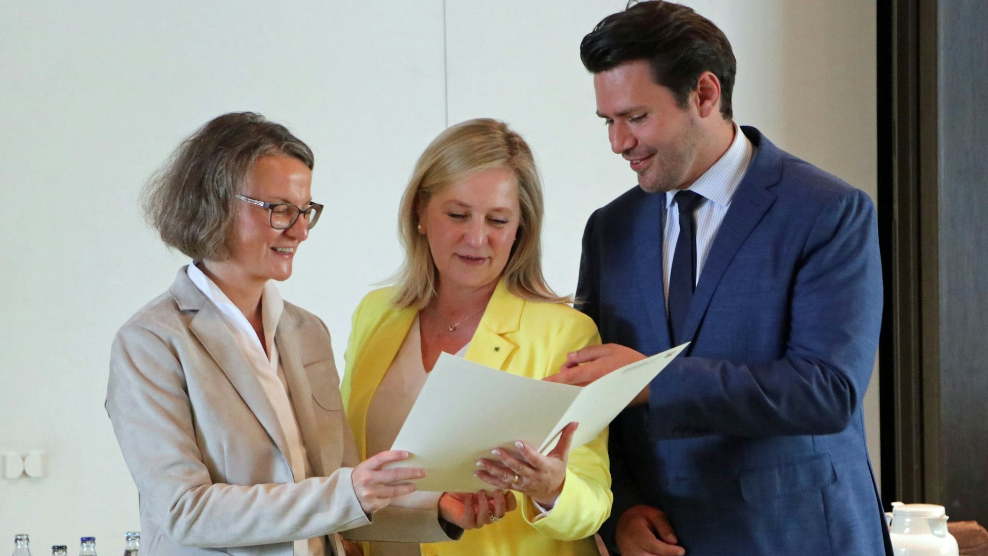 Das Foto zeigt drei Personen, die auf ein Dokument schauen.