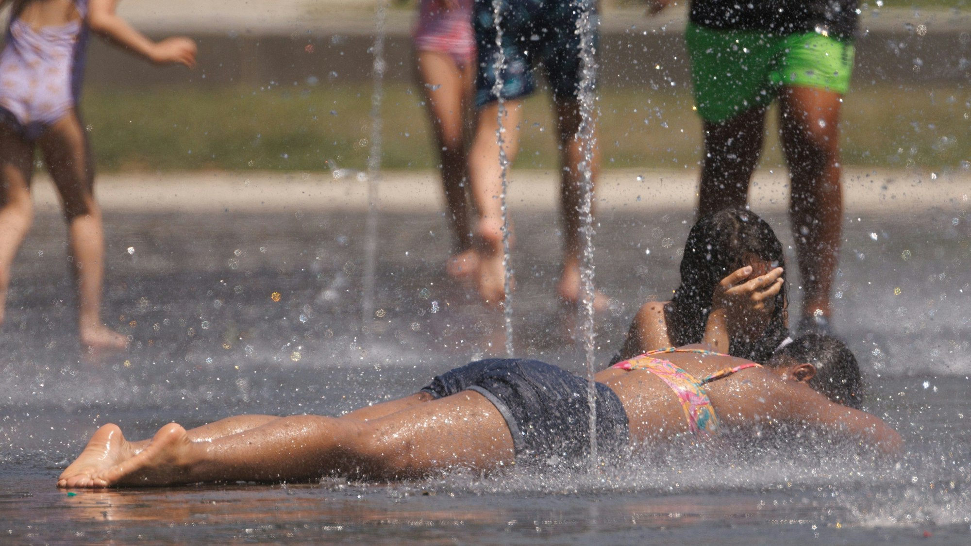 Kinder kühlen sich in einem Brunnen ab.