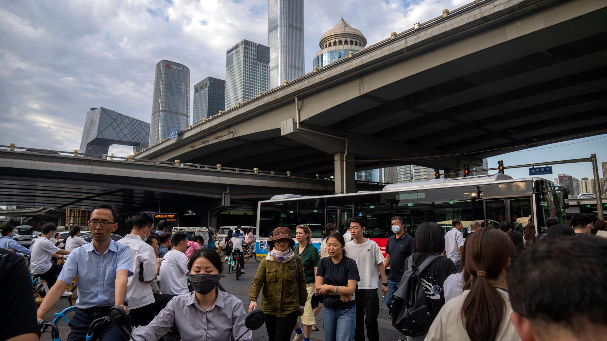Pendler überqueren am 13. Juni 2023 während der abendlichen Rushhour eine Kreuzung im zentralen Geschäftsviertel von Peking.
