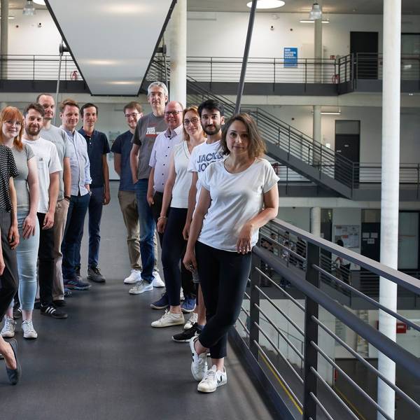 Mehrere Männer und Frauen stehen für ein Gruppenfoto in einem Treppenhaus zusammen.