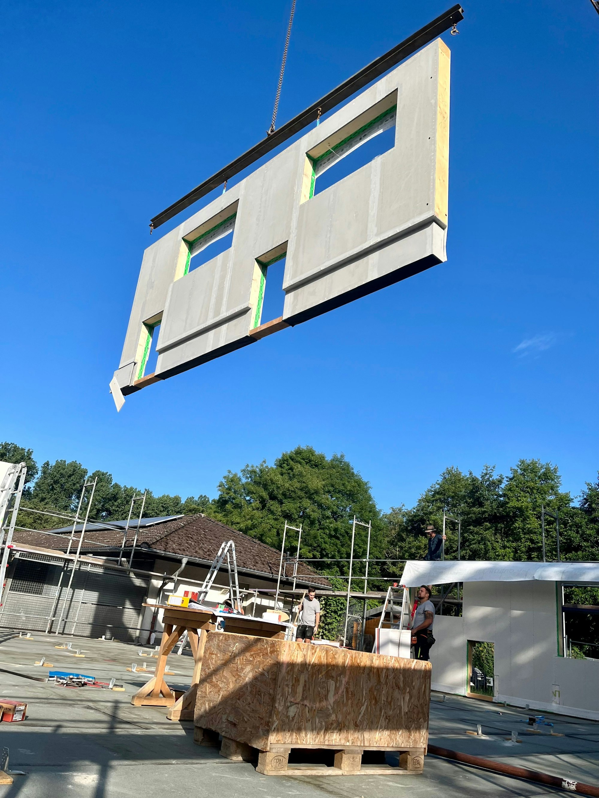 Wandteil am Kranhaken über der Baustelle.