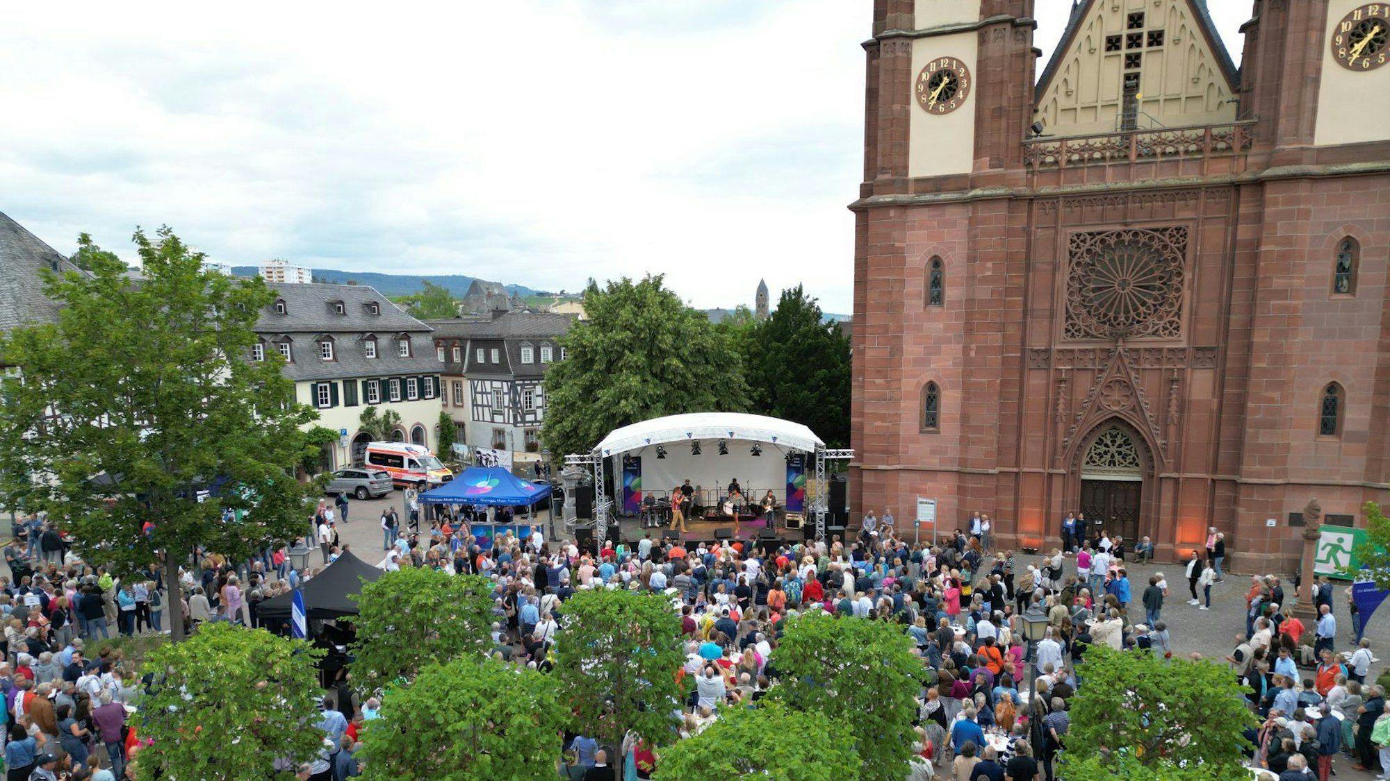 Direkt neben dem doppeltürmigen Dom ist eine Bühne aufgebaut, davor lauschen viele Menschen auf dem Domplatz den Musikern.