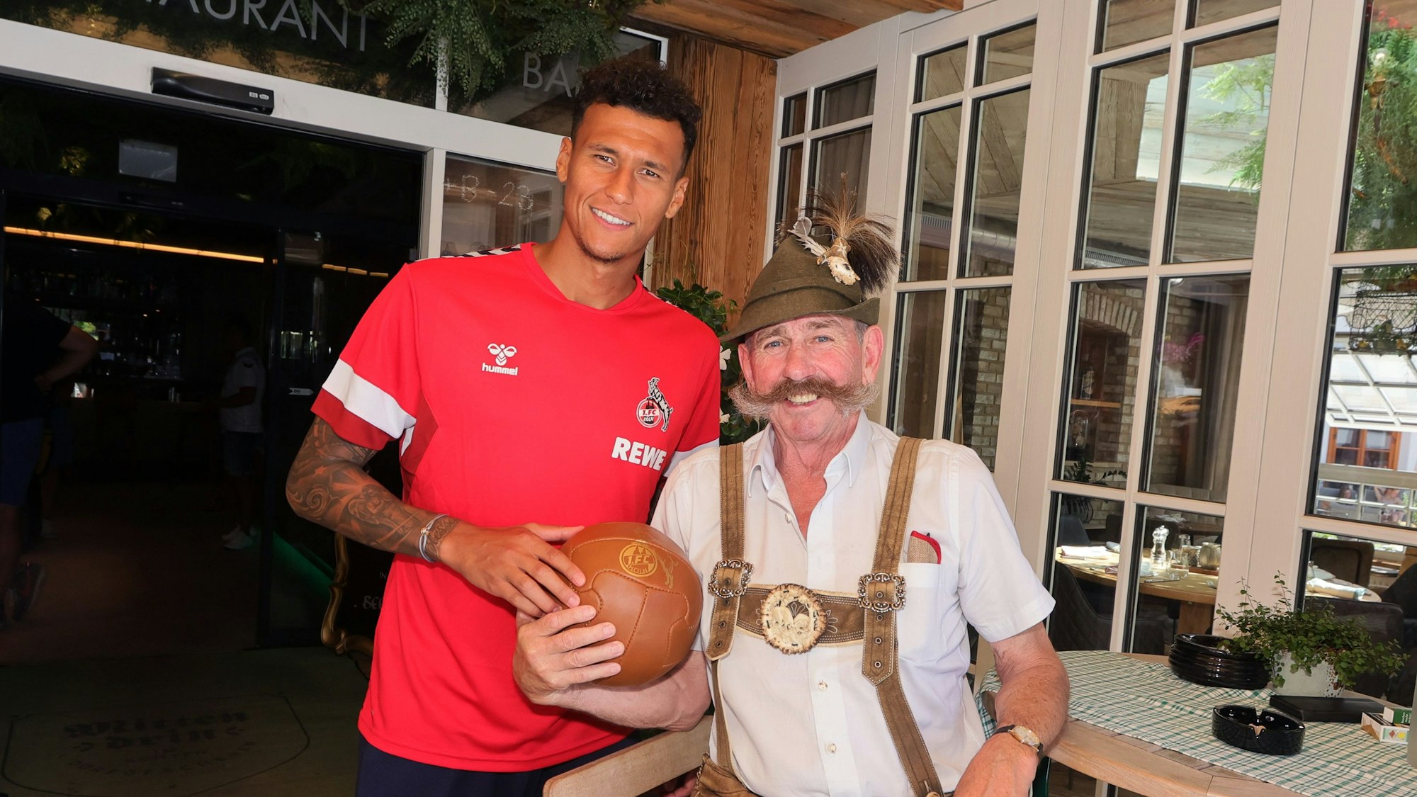 FC-Stürmer Davie Selke mit „Hangerl Hans", einem Original aus Maria Alm, vor dem Kölner Teamquartier Hotel Eder.