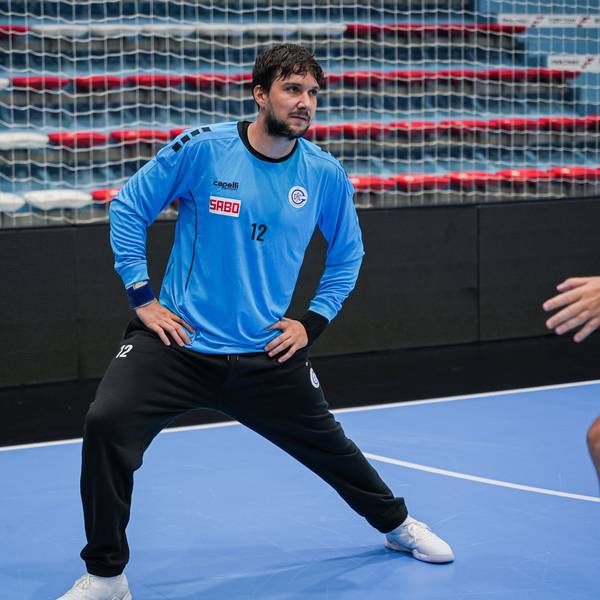 Ein Handball-Torhüter dehnt sich beim Training in einer Sporthalle.