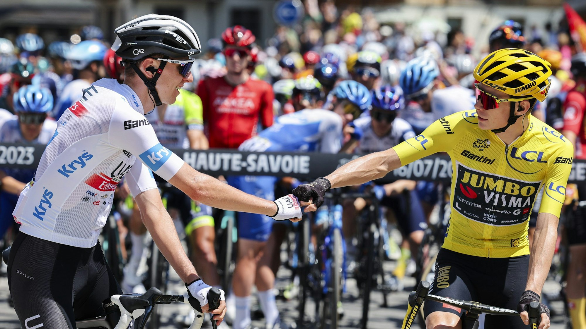 Tadej Pogacar (l) aus Slowenien von UAE Team Emirates und Jonas Vingegaard aus Dänemark von Jumbo-Visma begrüßen sich am Start der 15. Etappe.