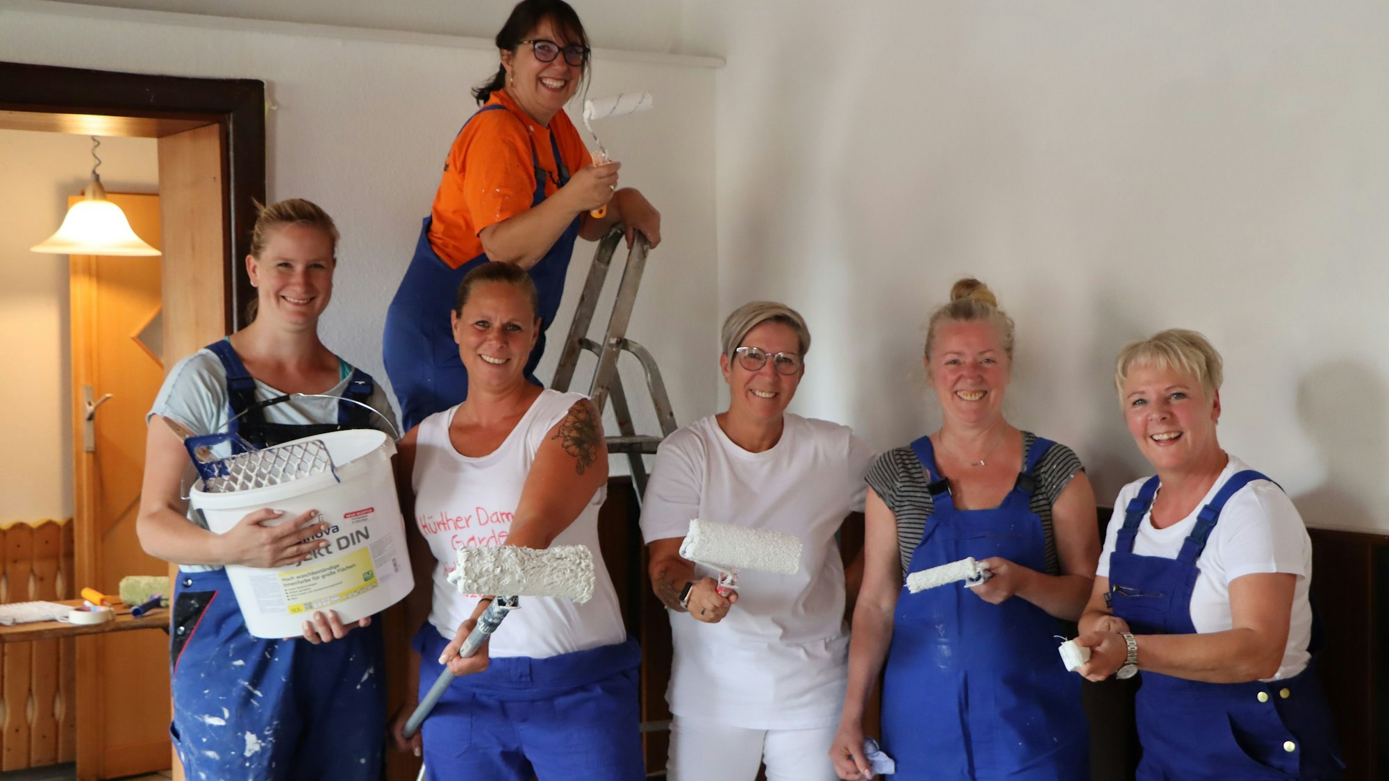 Mehrere Frauen der 1. Hürther Damengarde „Hürther Hätzje“ sind mit Pinseln, Rollen und Farbe auf dem Foto zu sehen.