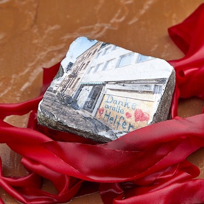 Zu sehen ist ein Pflasterstein mit einem Foto aus dem Wiederaufbau.