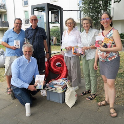 Menschen stehen vor dem Bücherschrank.