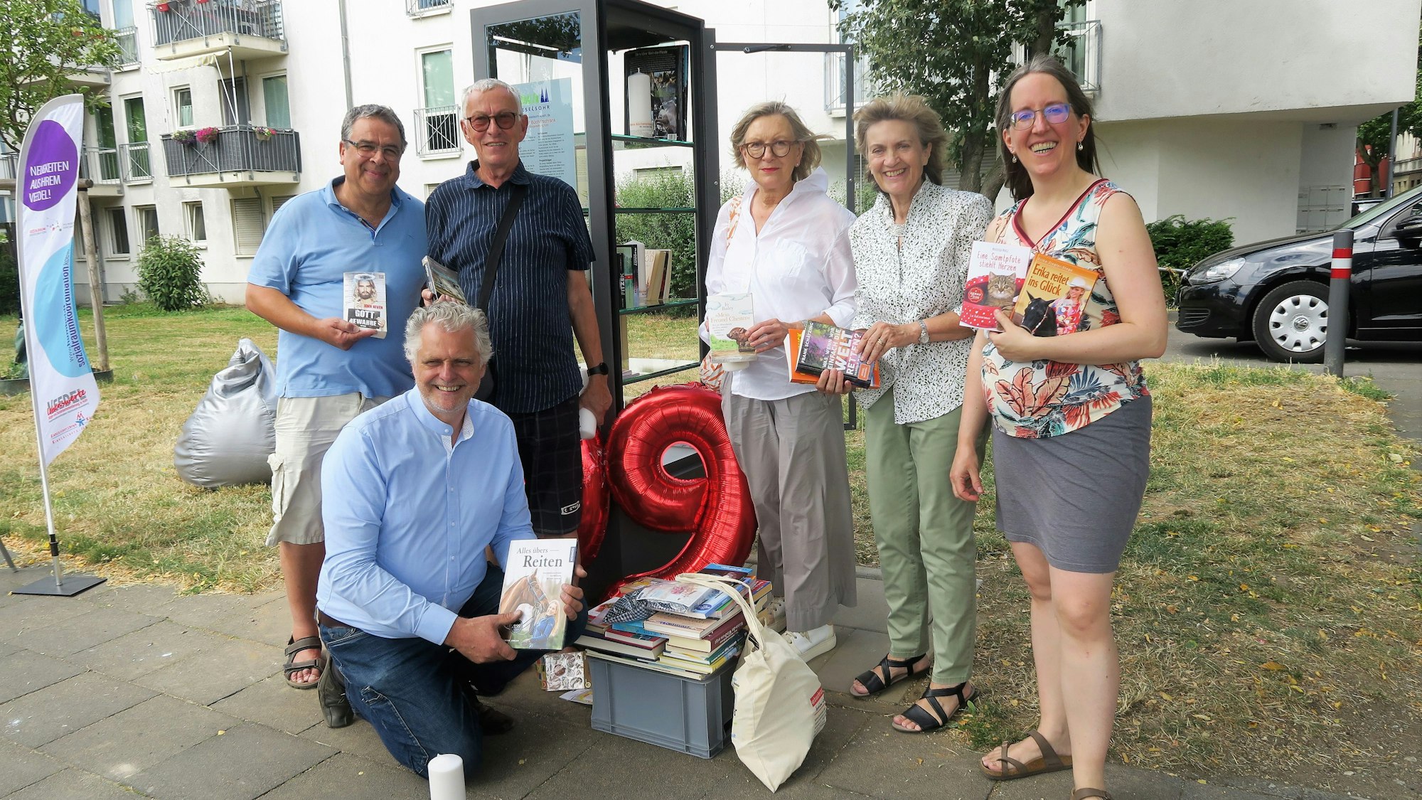 Menschen stehen vor dem Bücherschrank.