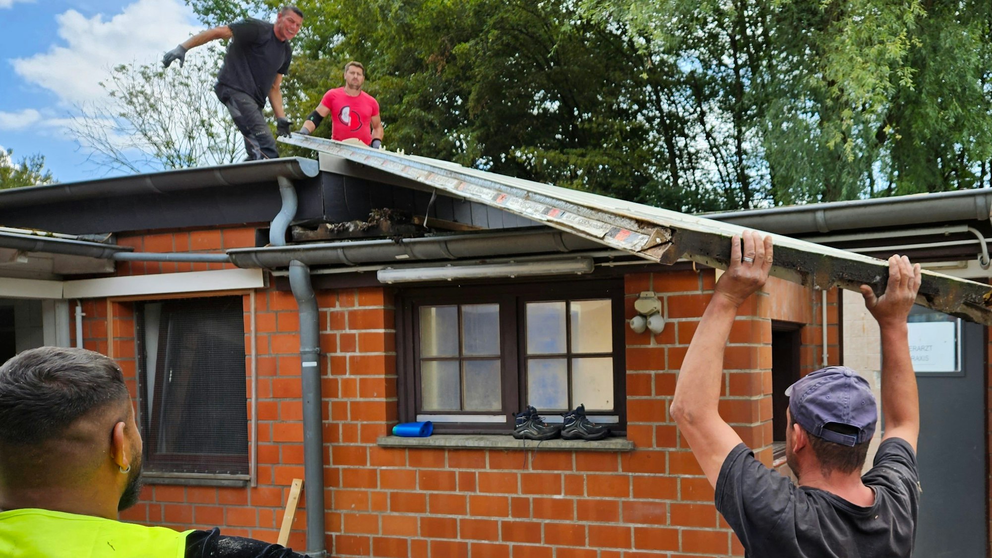 Männer heben ein altes Dach von einer Baracke. Das Tierheim in Niederaußem erhält Neubauten. Die alten Baracken werden abgerissen.