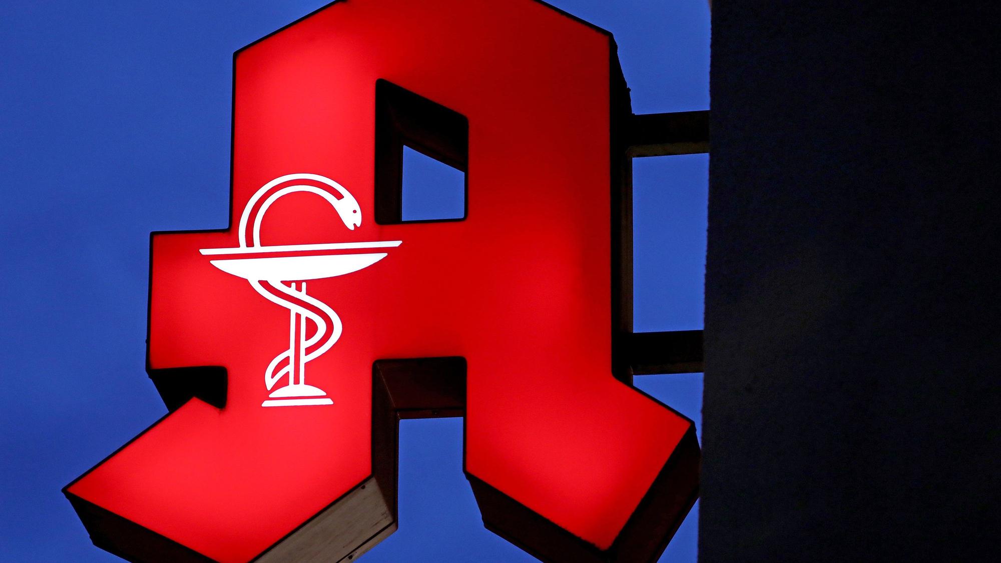 Das Apotheken-Logo leuchtet an einer Apotheke.