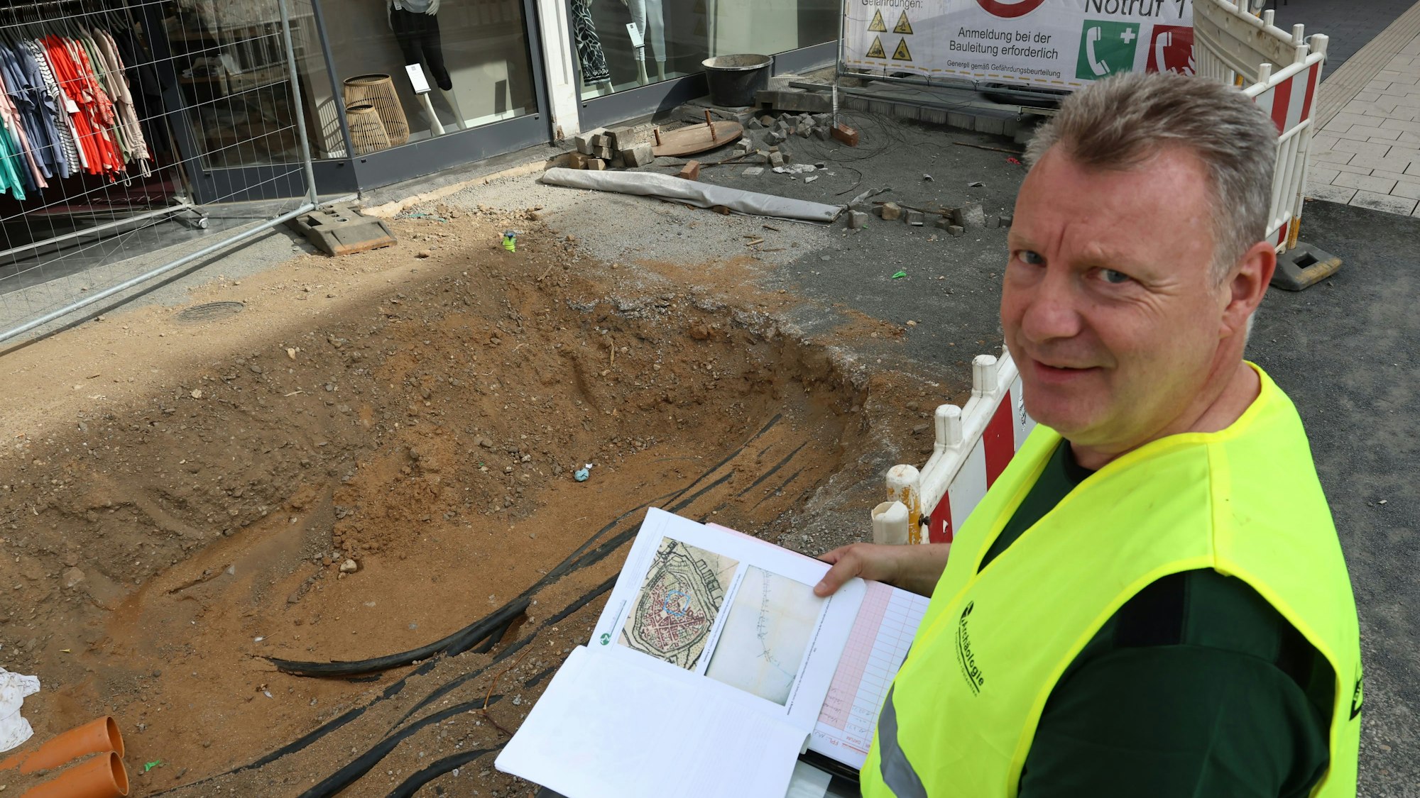 Der Grabungsleiter mit Unterlagen am Rande der Baugrube.