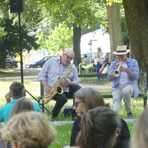 Bernd Delbrügge und Ebasa Pallada spielen auf einer Parkbank Saxofon und Trompete.