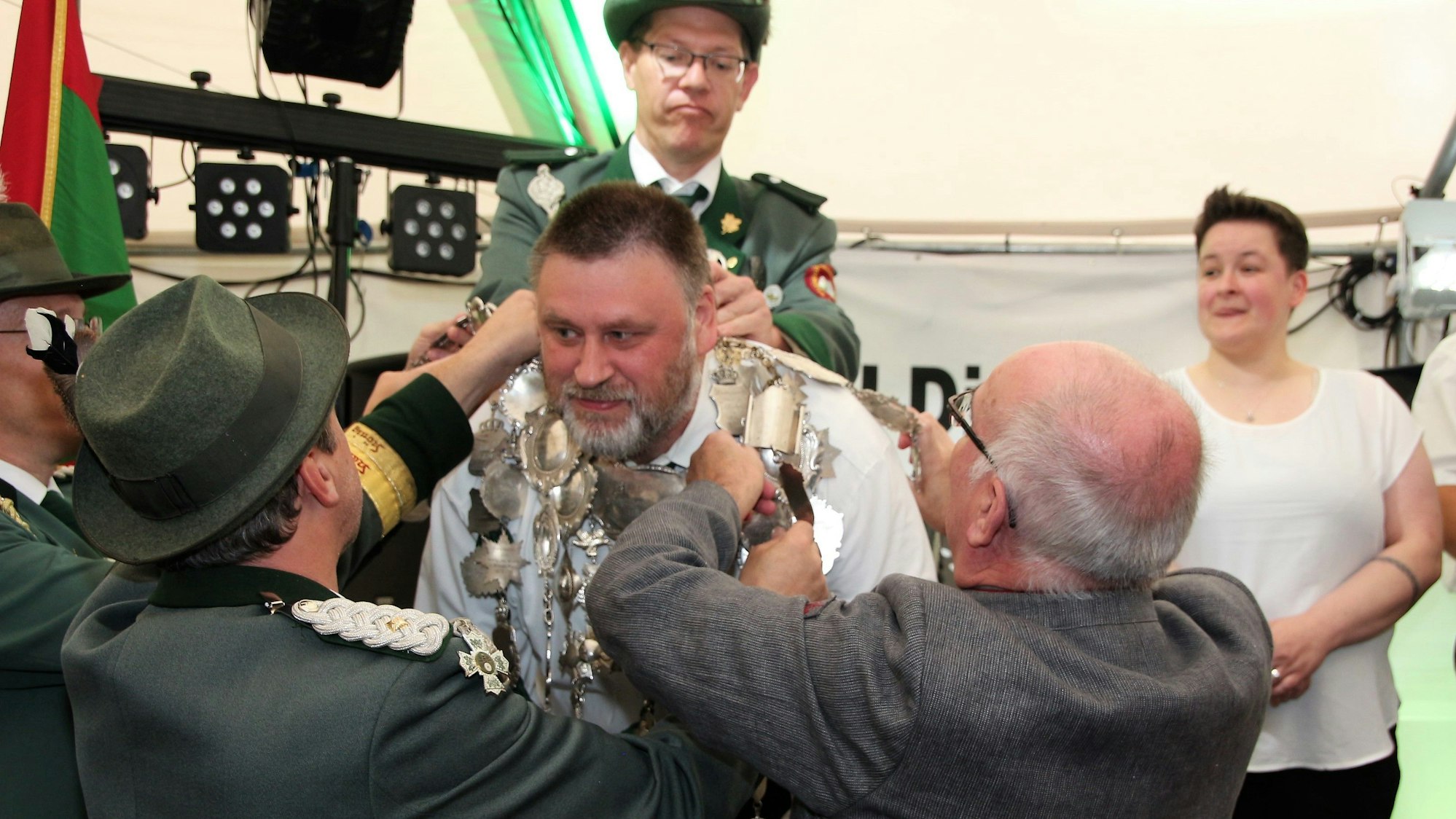 Schützen helfen Pastor Lambert Schäfer dabei, die schwere Königskette um den Hals von Christian Hartmann zu legen.