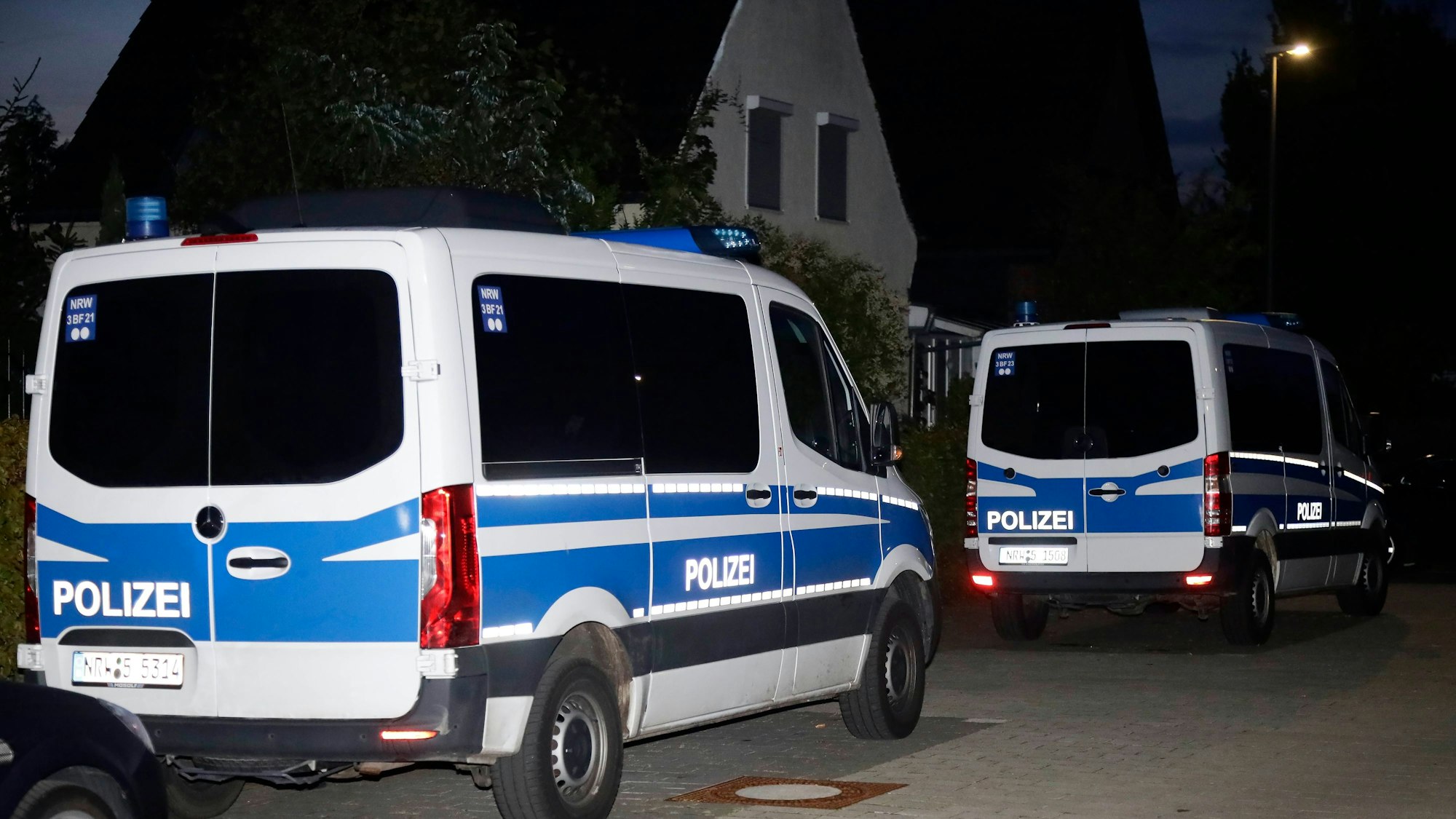 Mehrere Einsatzwagen der Polizei stehen vor einem Wohnhaus.