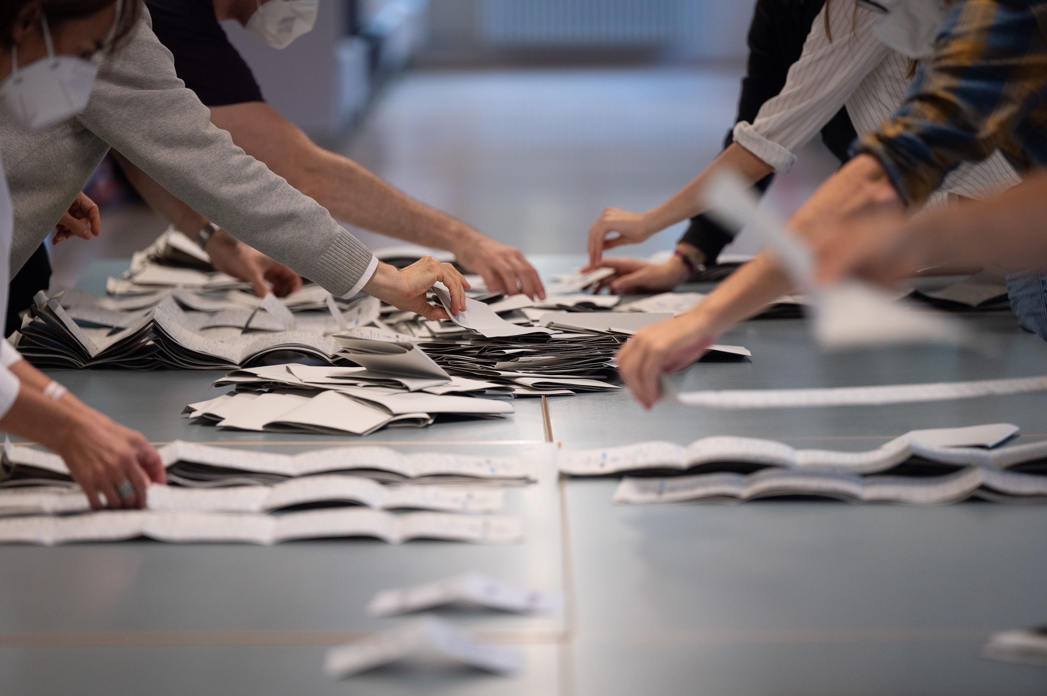 Wahlhelfer und Wahlhelferinnen zählen in einem Wahllokal Stimmzettel für die Bundestagswahl.