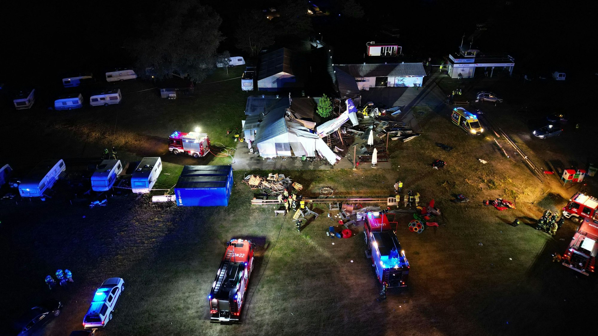Diese Luftaufnahme zeigt Einsatzfahrzeuge in der Nähe der Stelle, an der am 17. Juli 2023 ein Kleinflugzeug in einen Hangar auf einem Flugplatz im Dorf Chrcynno in der Nähe von Warschau stürzte und fünf Menschen tötete.