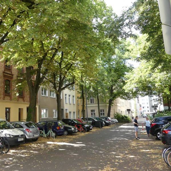 Eine Straße in Ehrenfeld mit Bäumen und geparkten Autos.