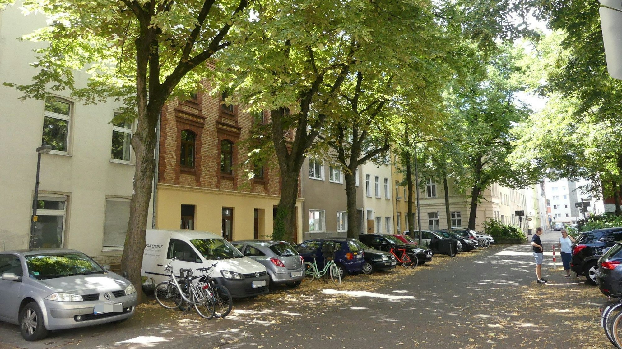Eine Straße in Ehrenfeld mit Bäumen und geparkten Autos.