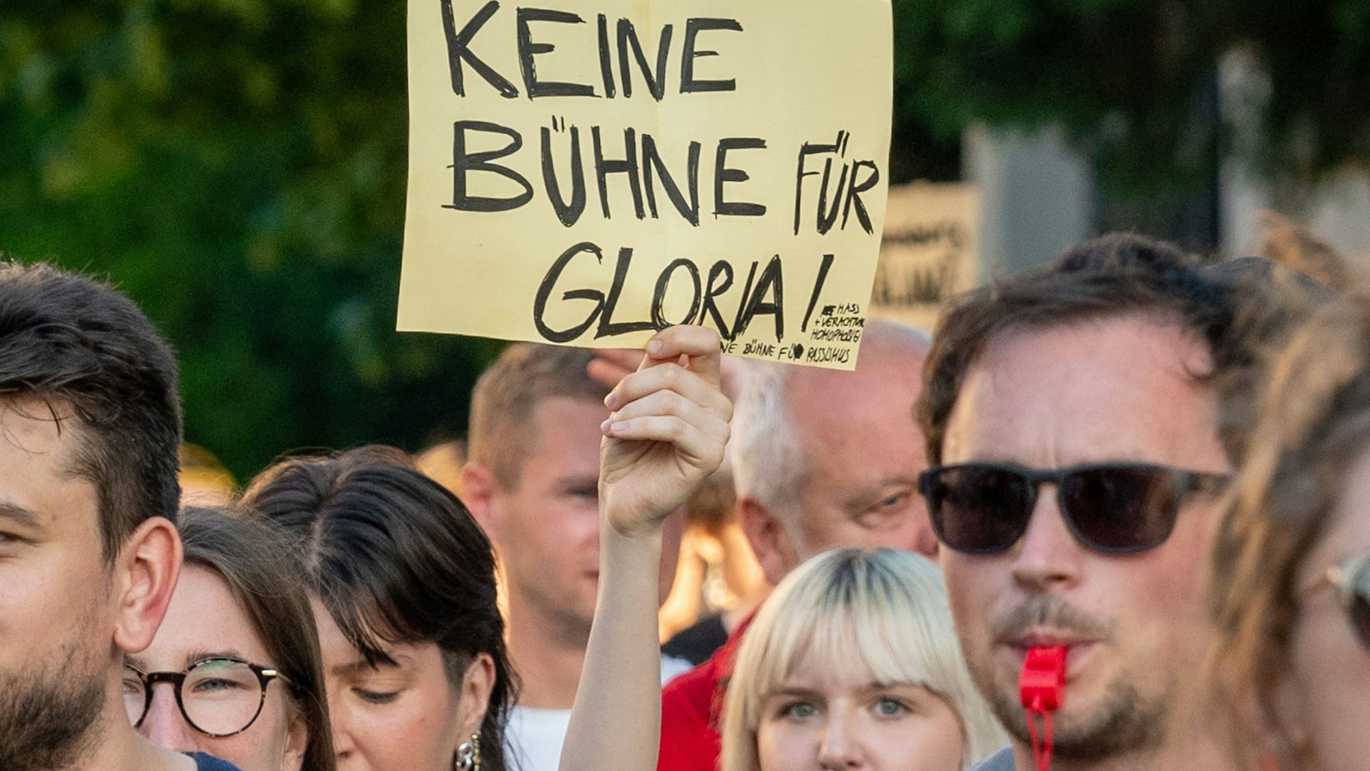 Ein Schild mit der Aufschrift „Keine Bühne für Gloria!“ wird während einer Demonstration vor dem Fürstenschloss St. Emmeram in die Höhe gehalten.