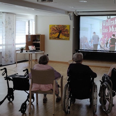 Senioren sitzen bei der digitalen Museumsführung im Burscheider Altenheim Luchtenberg-Richartz-Haus vor der Leinwand.