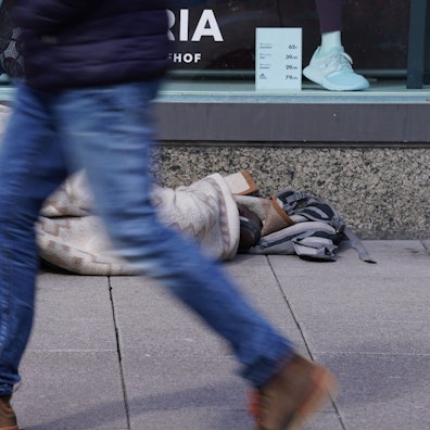 AEin Obdachloser liegt vor einem Schaufenster von Galeria Karstadt Kaufhof.