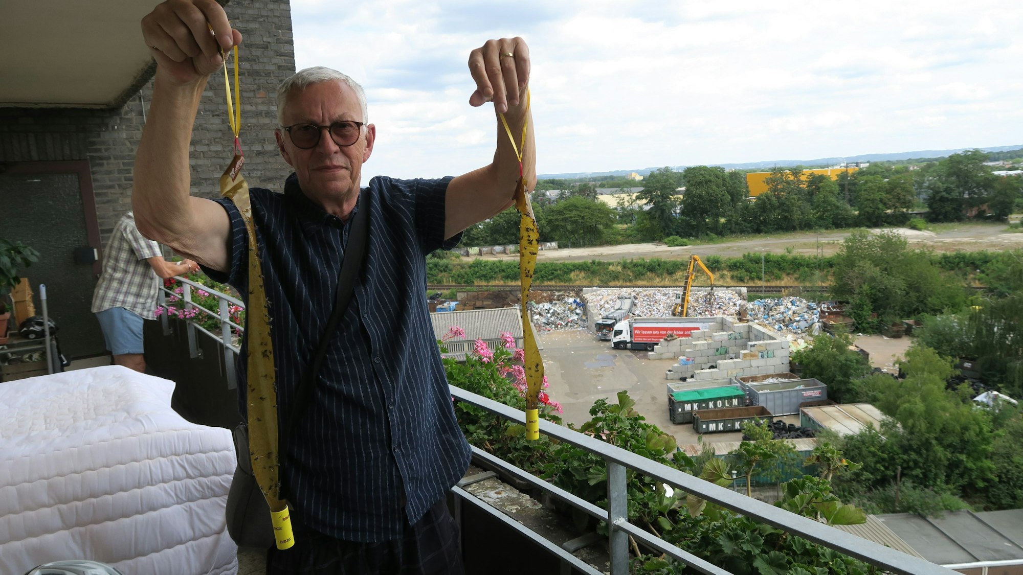 Peter Peterlini mit Fliegenfängern auf dem Balkon. Im Hintergrund das Presswerk.