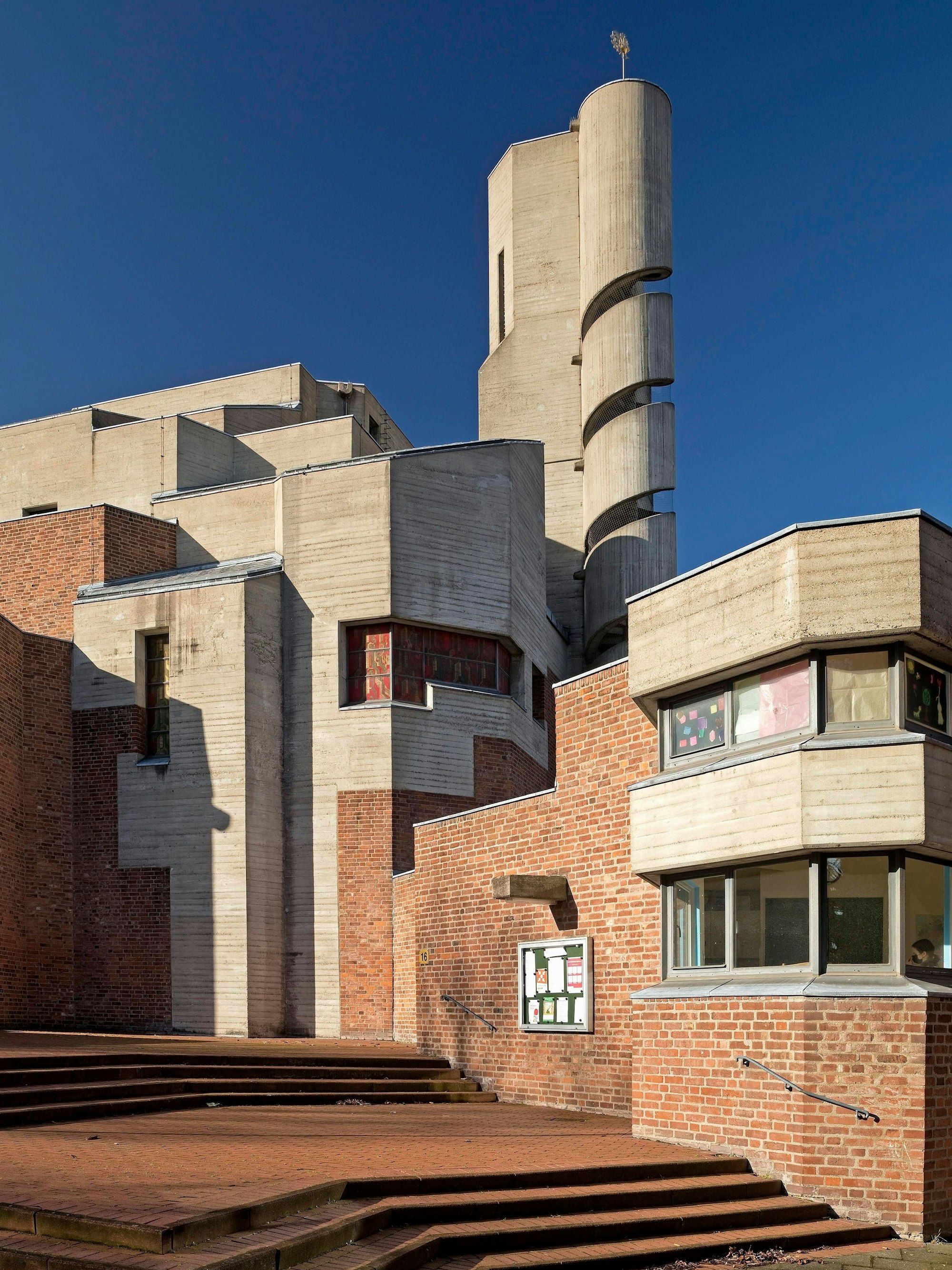 Blick auf die katholische Kirche Christi Auferstehung in Lindenthal mit Backsteinfassade und einem gewundenen Betonturm