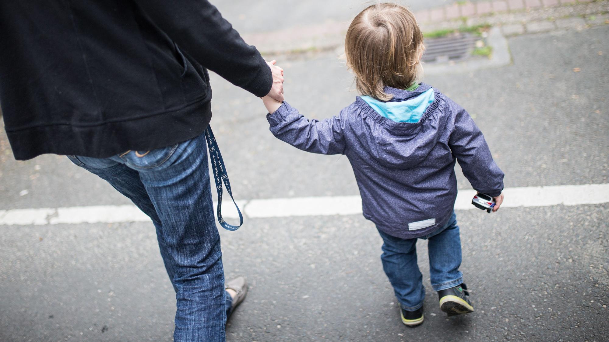 Eine Frau geht mit einem kleinen Kind an der Hand auf der Straße.