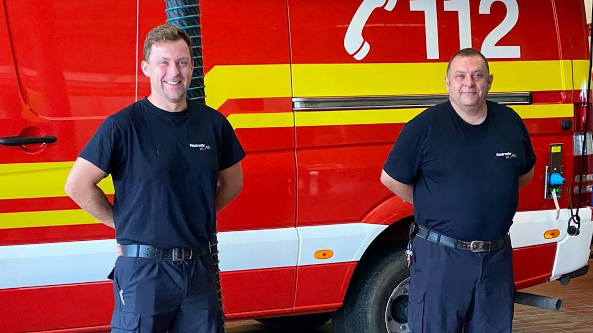 Zwei Männer stehen vor einem Einsatzwagen.