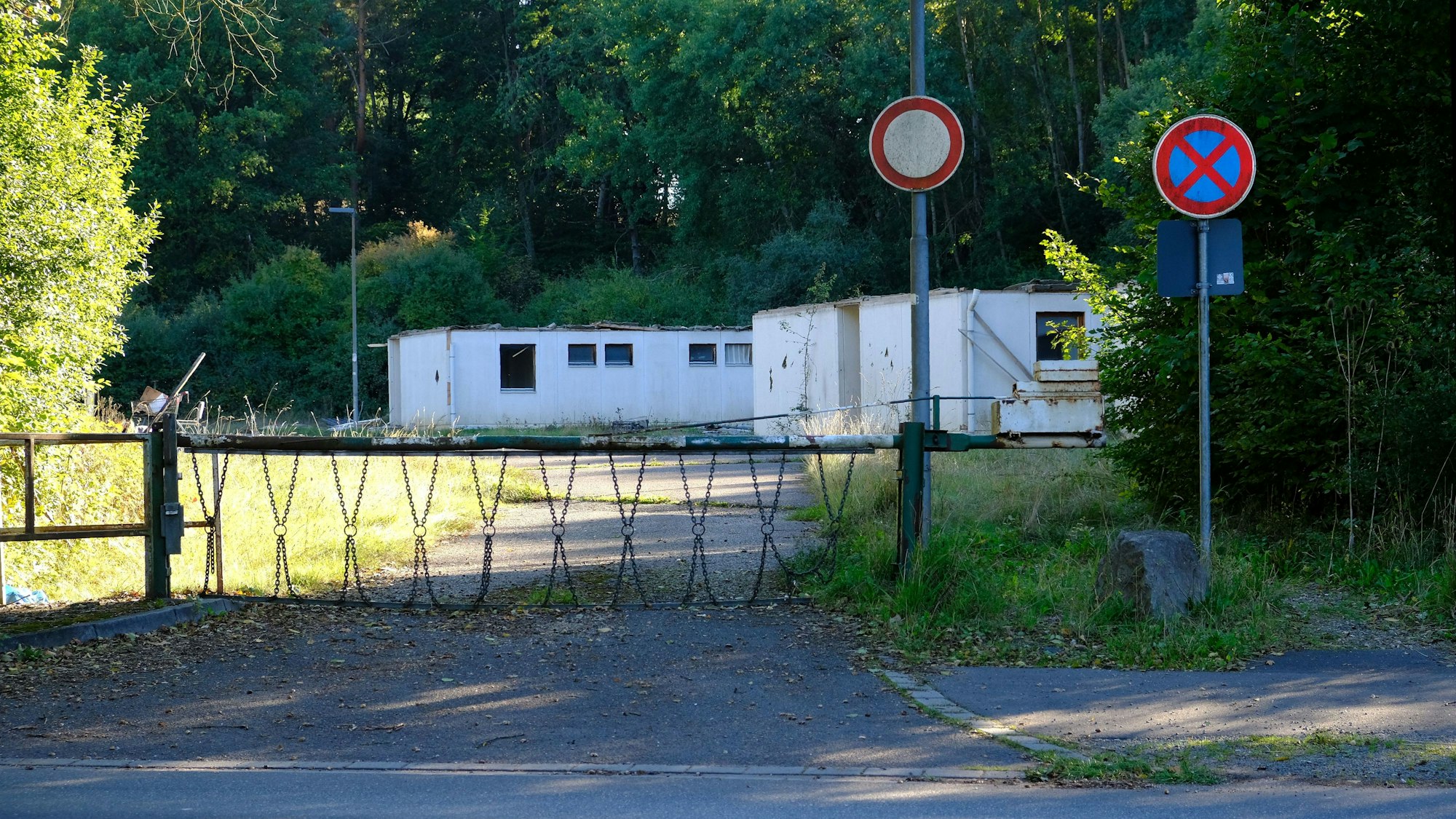 Auf einem mit einer Schranke gesicherten Gelände stehen abrissreife Notunterkünfte.