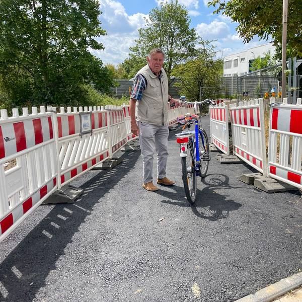 Wolfgang Sauerteig steht mit seinem Fahrrad auf einem geteerten Weg.