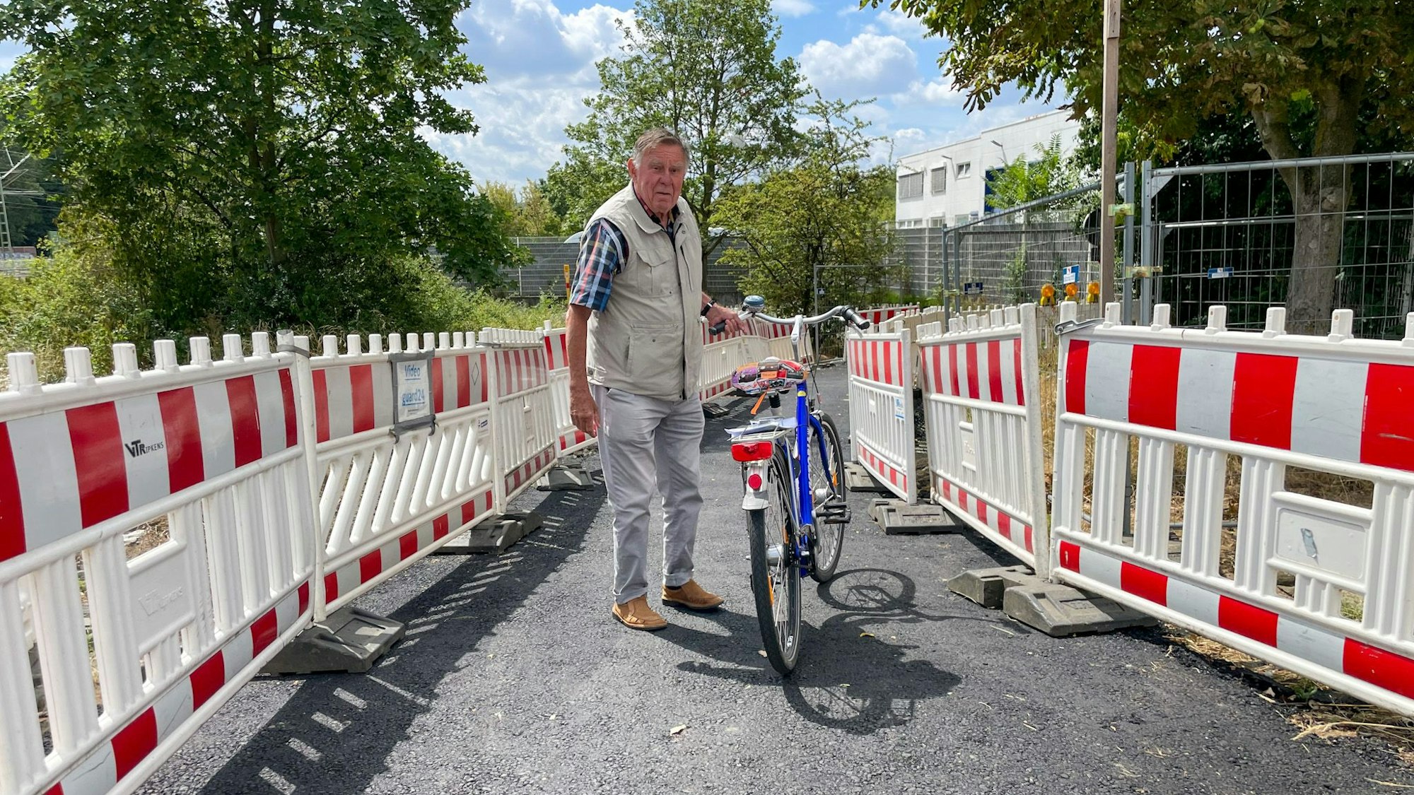 Wolfgang Sauerteig steht mit seinem Fahrrad auf einem geteerten Weg.