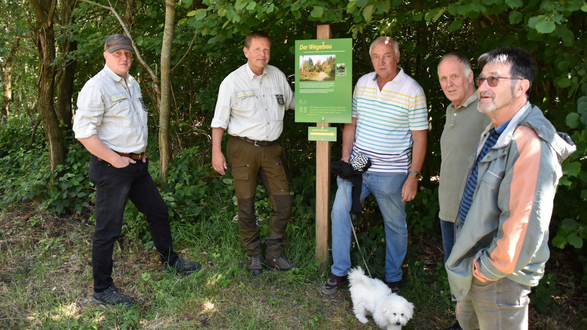 Die Initiatoren des Holzwegs in Much stehen vor der Infotafel zum Thema Wegebau.