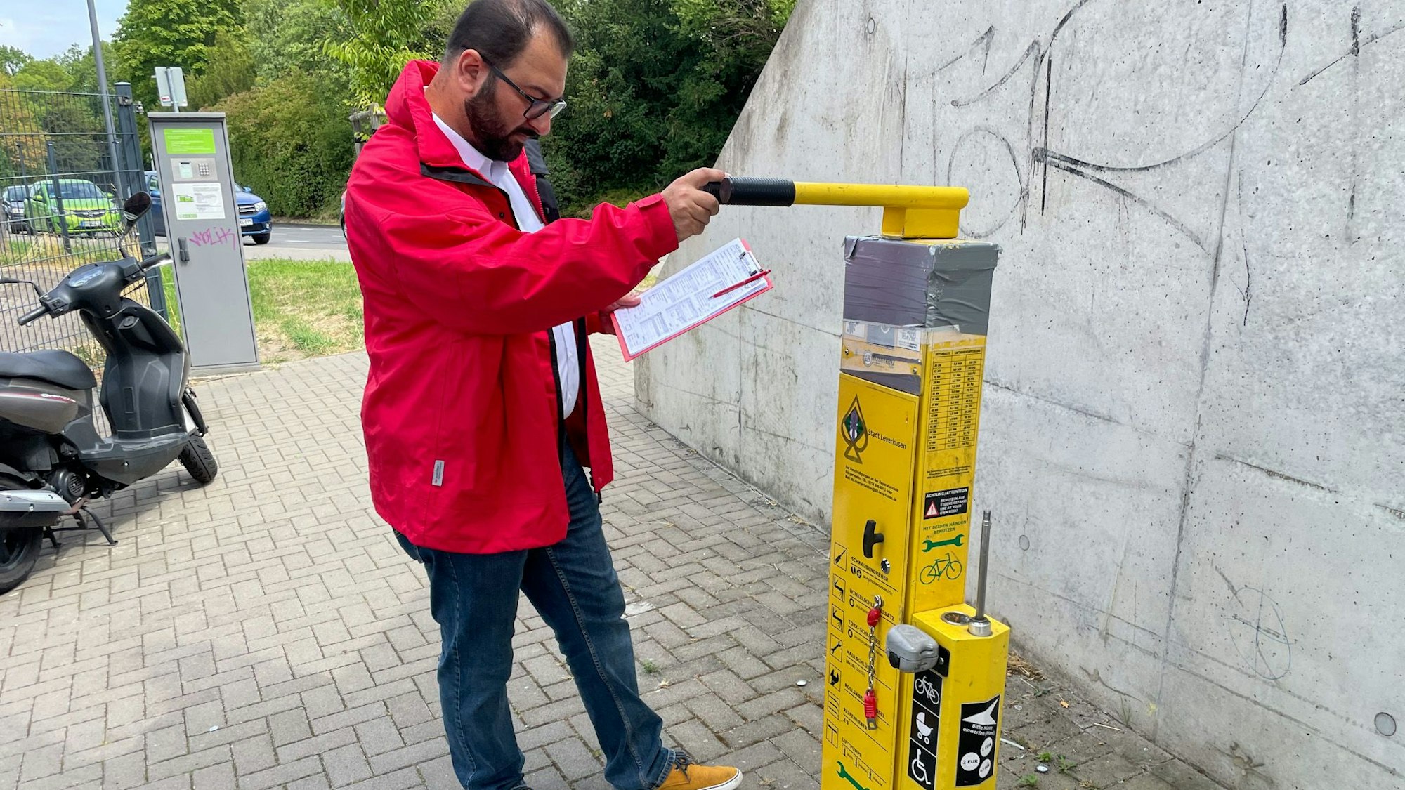 Tolga Kaya (Regionalbeautragter) schaut sich die Fahrradreparaturstation in Opladen an.