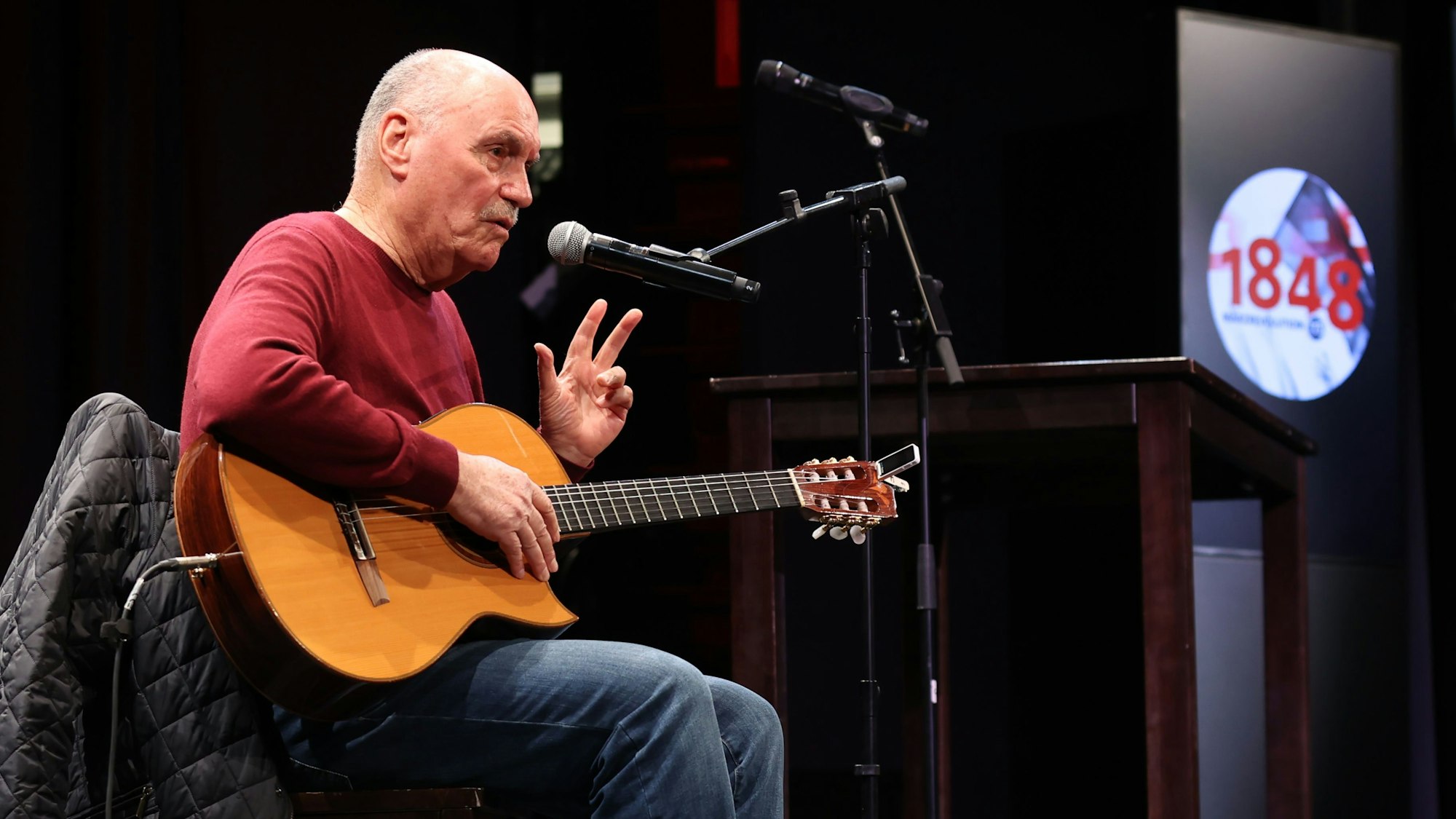 Rolly Brings sitzt mit seiner Gitarre auf der Bühne.