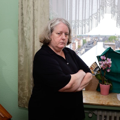 Hildegart Scholten (Name geändert) steht mit verschränkten Armen vor dem Fenster ihrer Wohnung. Sie wird permanent von Geräuschen eines Funkmastes auf dem Dach ihrer Wohnung gestört.