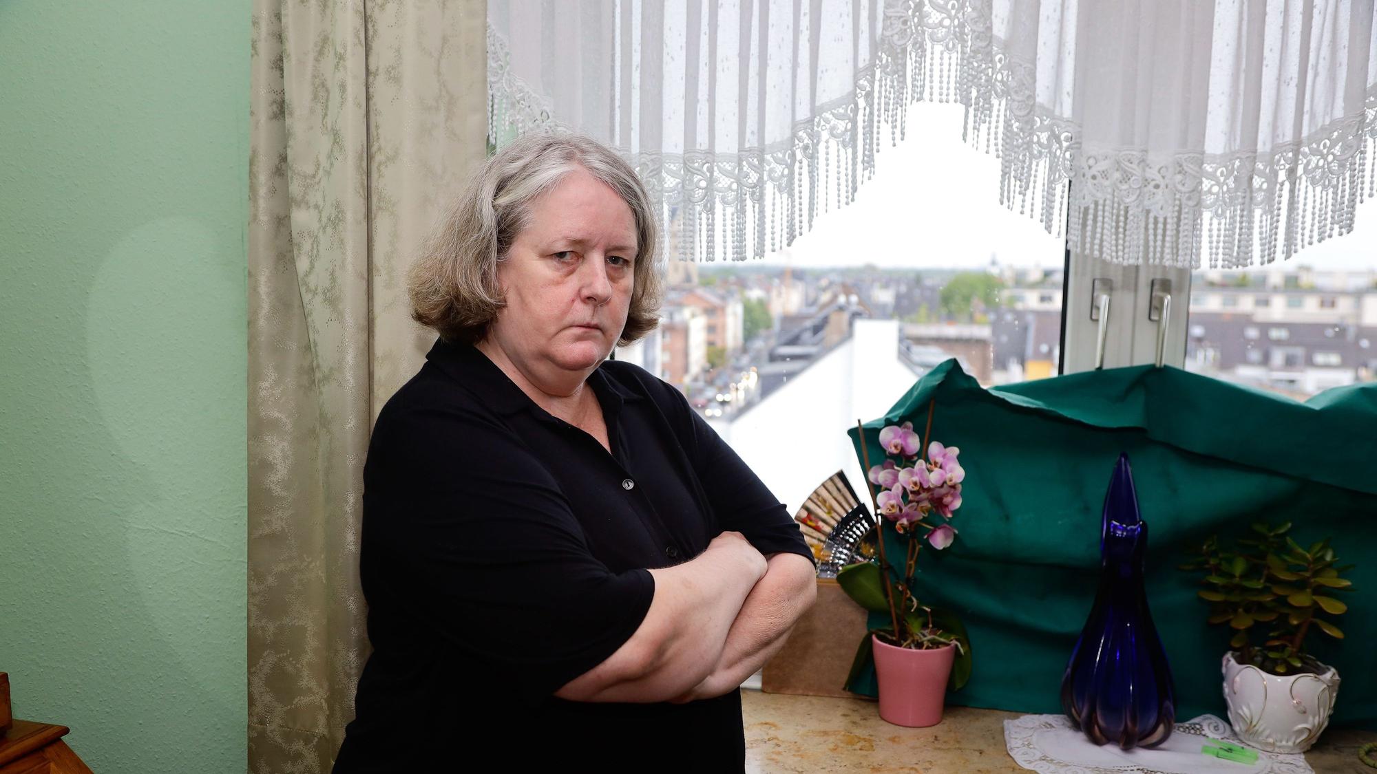 Hildegart Scholten (Name geändert) steht mit verschränkten Armen vor dem Fenster ihrer Wohnung. Sie wird permanent von Geräuschen eines Funkmastes auf dem Dach ihrer Wohnung gestört.