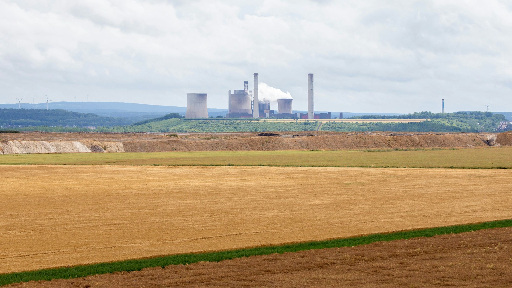 Blick auf den Braunkohletagebau Inden bei Jülich mit landwirtschaftlichen Nutzflächen, im Hintergrund ist das Braunkohlekraftwerk Weisweiler zu sehen.