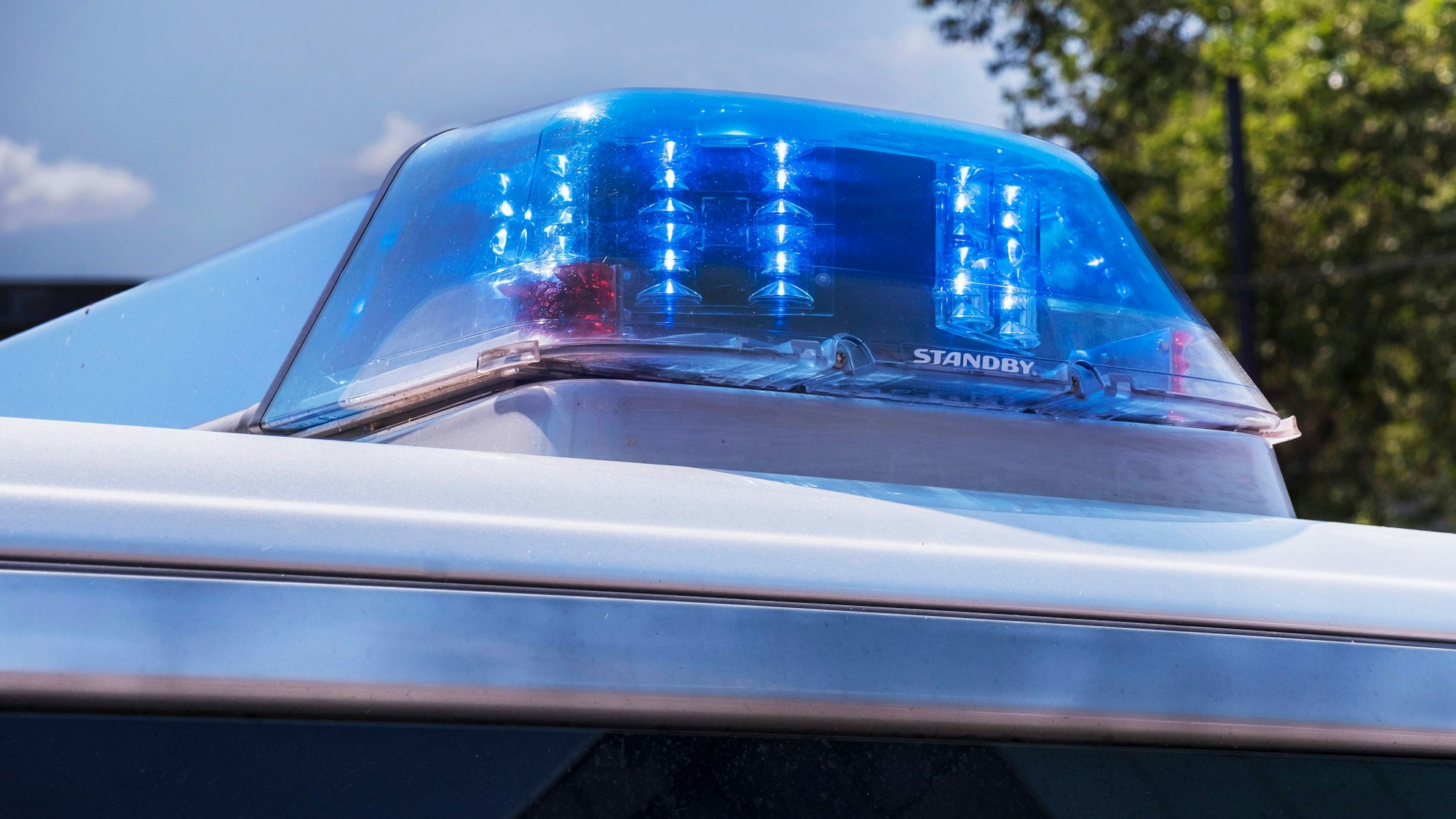 An einem Polizeiwagen blinkt ein Blaulicht.