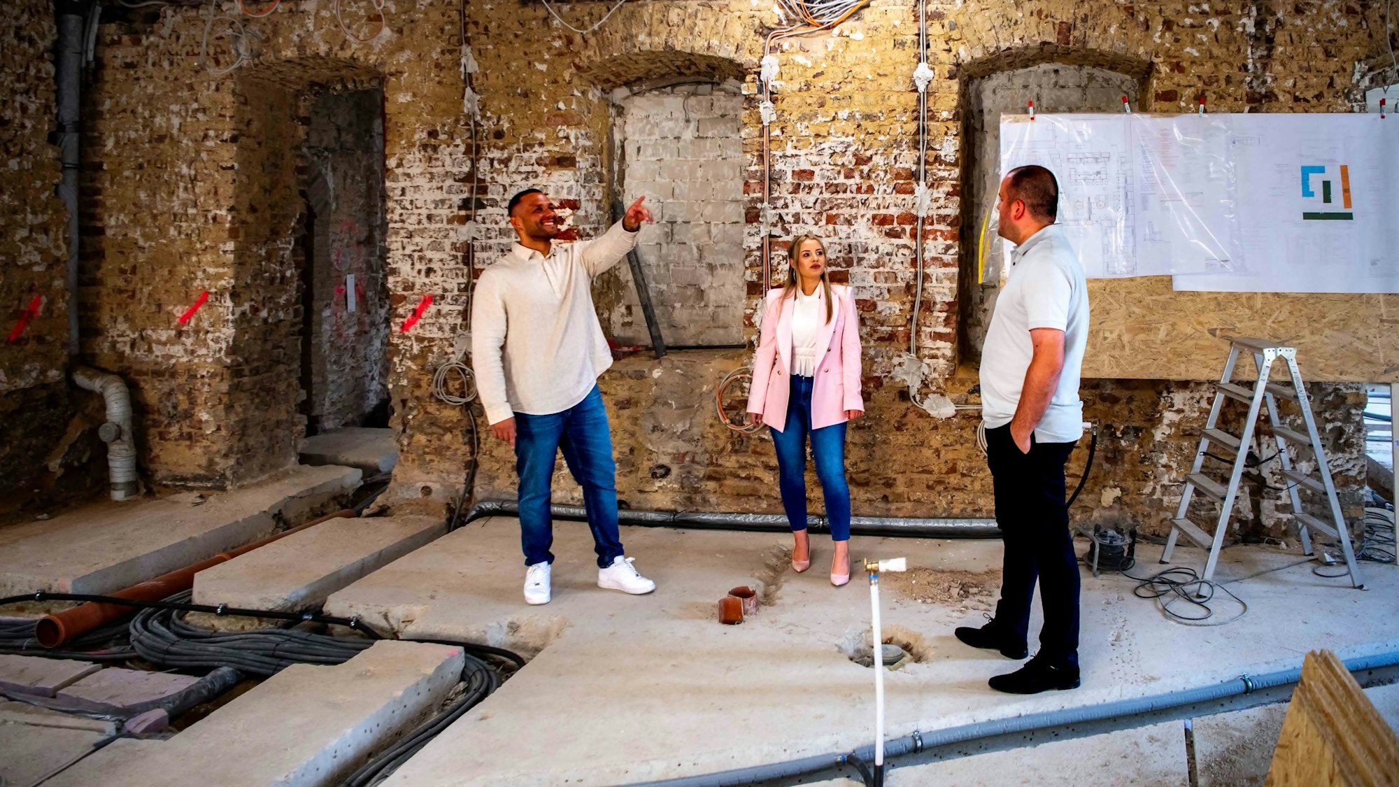 Die drei Betreiber stehen in ihrem entkernten Lokal und schauen sich um.