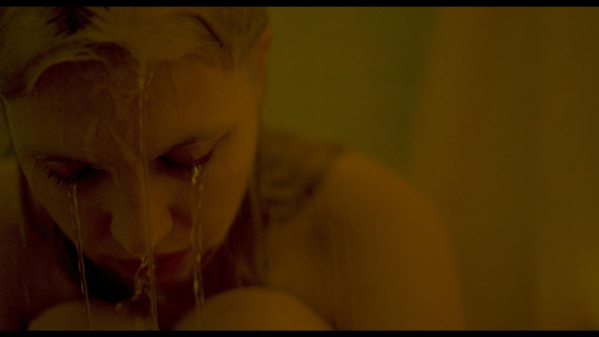 Eine junge Frau sitzt in der Dusche und wird nass.