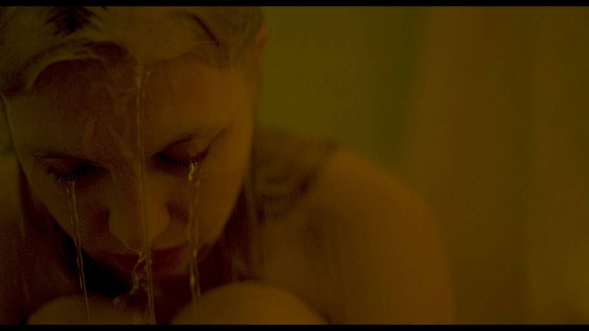 Eine junge Frau sitzt in der Dusche und wird nass.