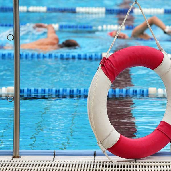 Ein Rettungsring hängt in einem Freibad am Rand des Beckens.
