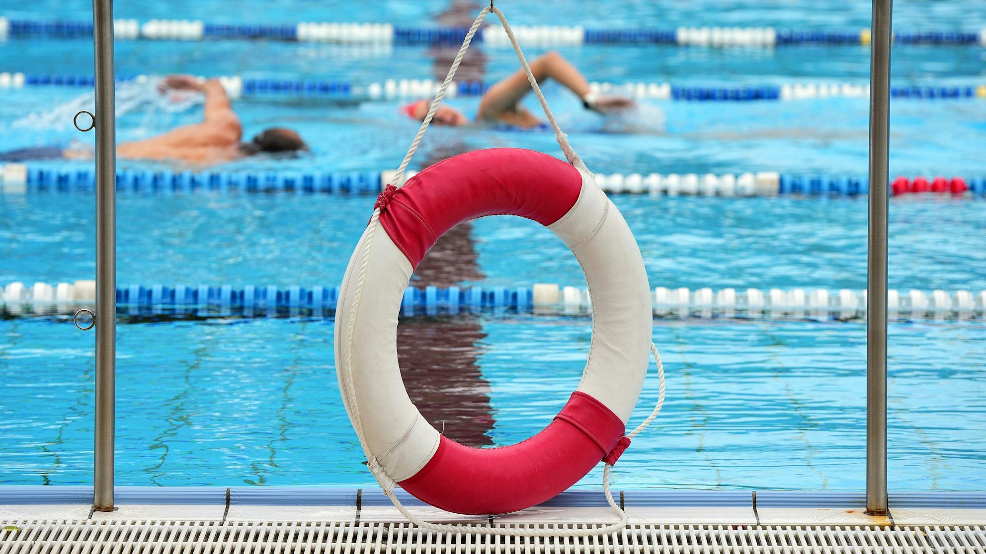 Ein Rettungsring hängt in einem Freibad am Rand des Beckens.