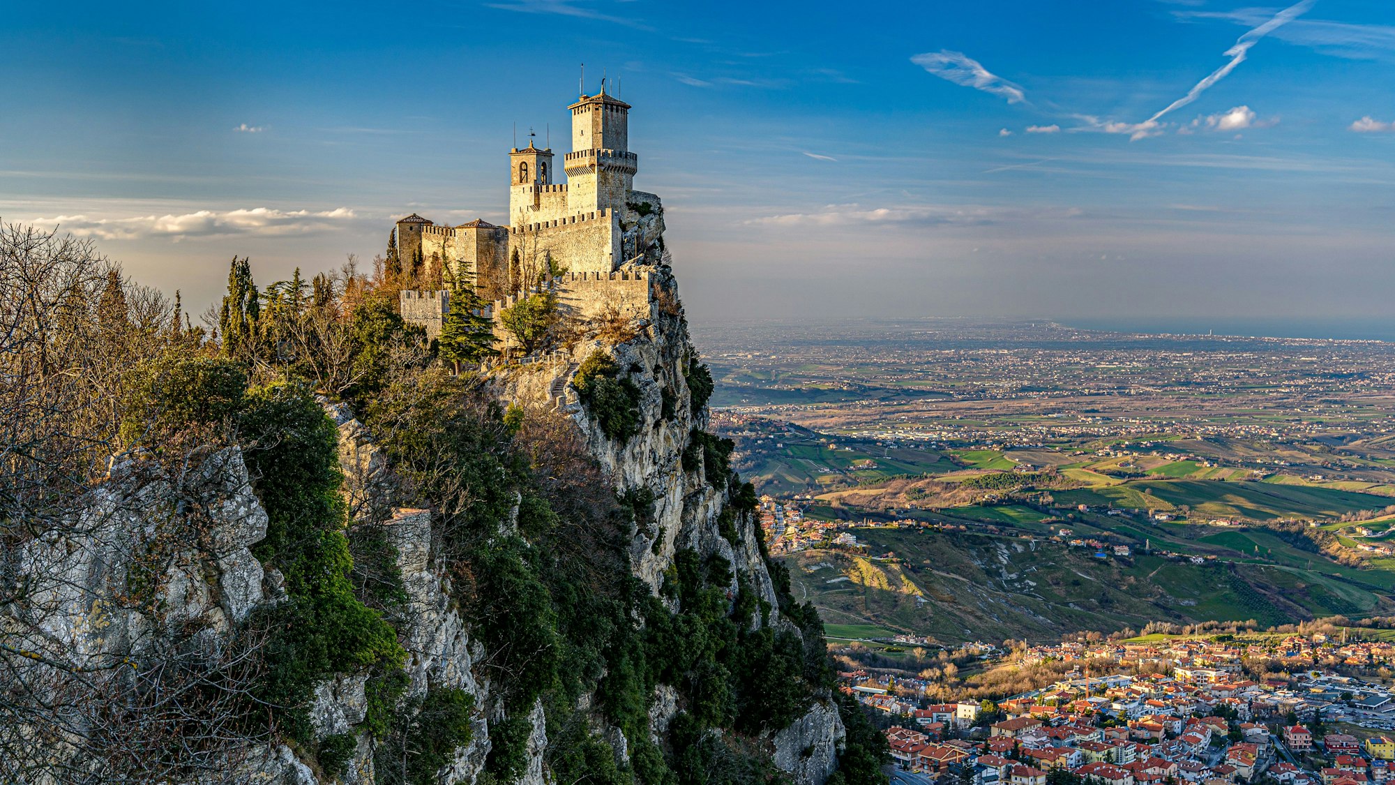 Guaita Tower im warmen Nachmittagslicht. Die Sonne scheint und der Himmel ist blau mit weißen, flauschigen Wolken.